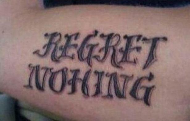 Ein Tattoo auf einem Arm zeigt den Schriftzug „Regret Nothing“.