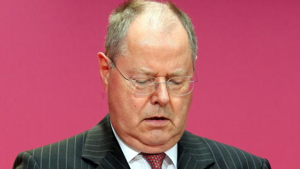 Ein Mann mit Brille und Anzug blickt nach unten.