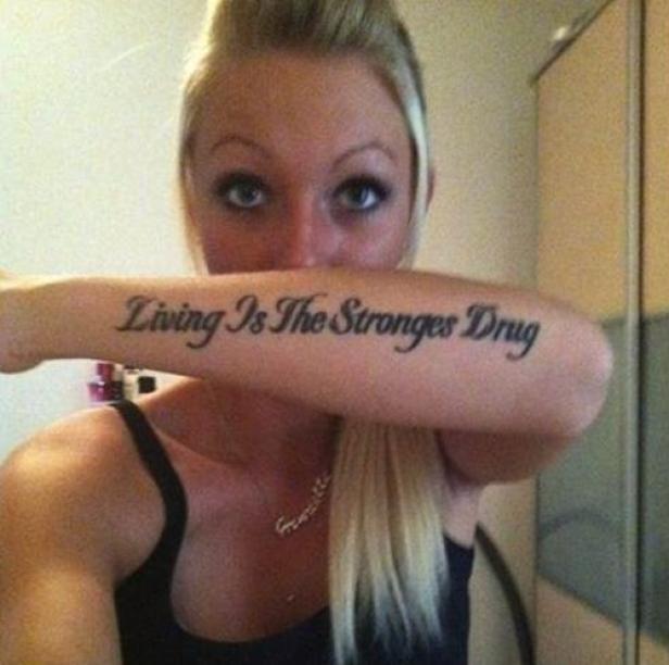 Eine Frau zeigt ihr Tattoo mit der Aufschrift „Living Is The Strongest Drug“.