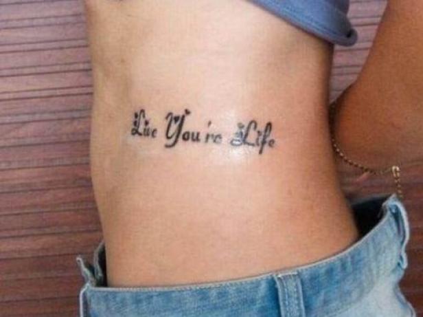 Ein Tattoo mit der Aufschrift „Live You're Life“ auf der Seite einer Person.