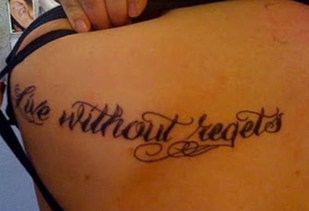 Ein Tattoo mit dem Schriftzug „Live without regrets“ auf der Haut einer Person.