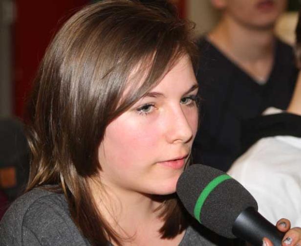 Eine junge Frau spricht in ein Mikrofon.