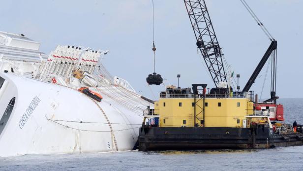 Die „Costa Concordia“ liegt auf der Seite, während ein Kran an der Bergung arbeitet.
