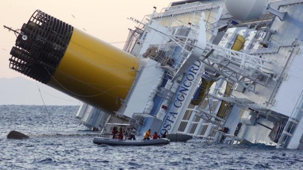 Die havarierte „Costa Concordia“ liegt im Wasser, ein Rettungsboot nähert sich.