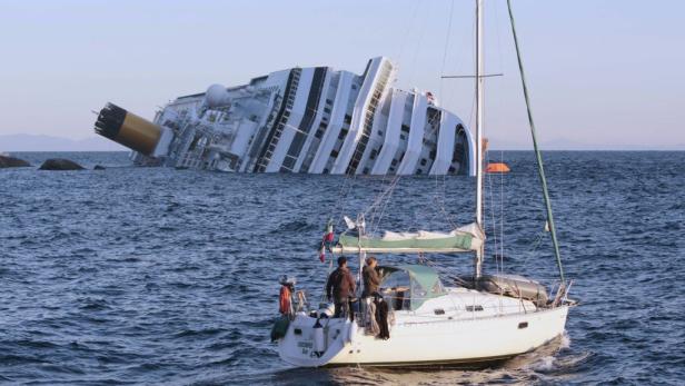 Ein Segelboot fährt an dem havarierten Kreuzfahrtschiff Costa Concordia vorbei.
