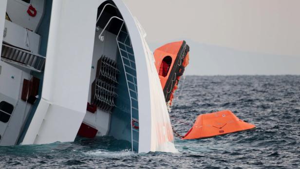 Ein gekentertes Schiff mit Rettungsinseln im Wasser.