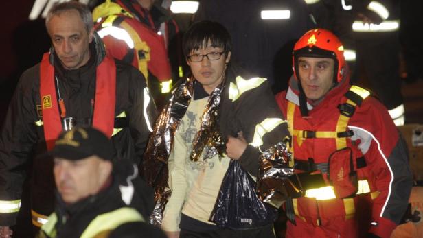 Ein geretteter Mann wird von Rettungskräften in Empfang genommen und mit einer Rettungsdecke gewärmt.