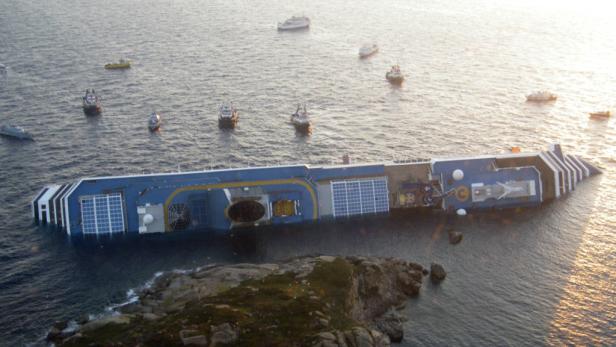 Das havarierte Kreuzfahrtschiff Costa Concordia liegt vor der Küste auf der Seite.