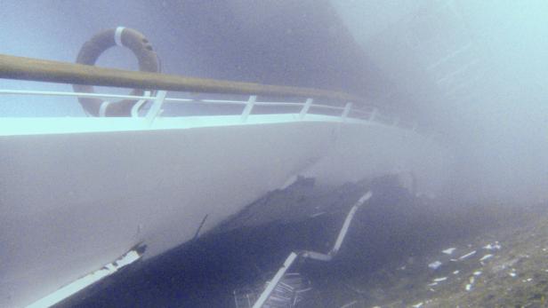 Unterwasseransicht eines Schiffswracks mit Rettungsring und beschädigter Struktur.