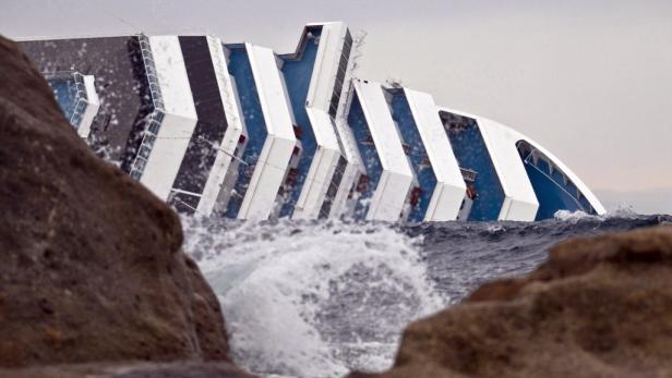 Ein gekentertes Kreuzfahrtschiff liegt auf der Seite im Meer.