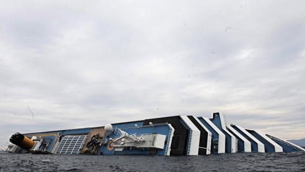 Ein gekentertes Kreuzfahrtschiff liegt auf der Seite im Wasser.