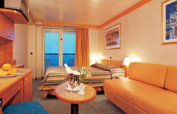 Einladende Kabine mit Balkon, Sekt und Obst auf einem Kreuzfahrtschiff.