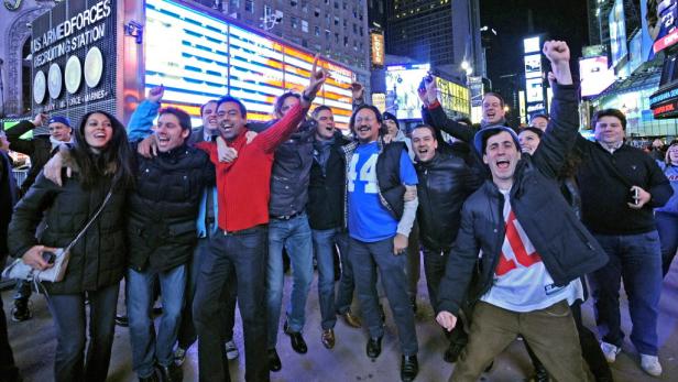Eine Gruppe von Menschen jubelt auf dem Times Square in New York City.