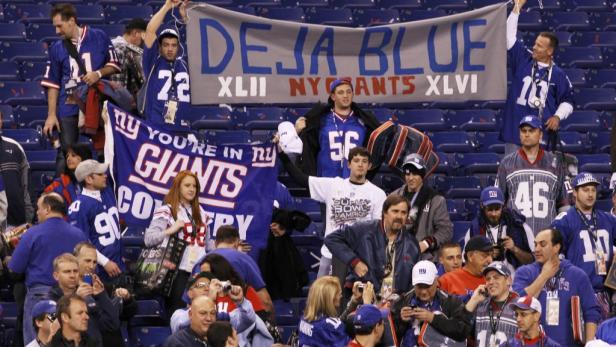 Eine Menschenmenge, die New York Giants-Trikots und -Banner bei einem Spiel trägt.