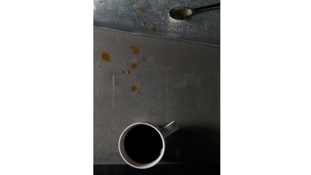 Eine Tasse Kaffee steht auf einer schmutzigen Metalloberfläche.