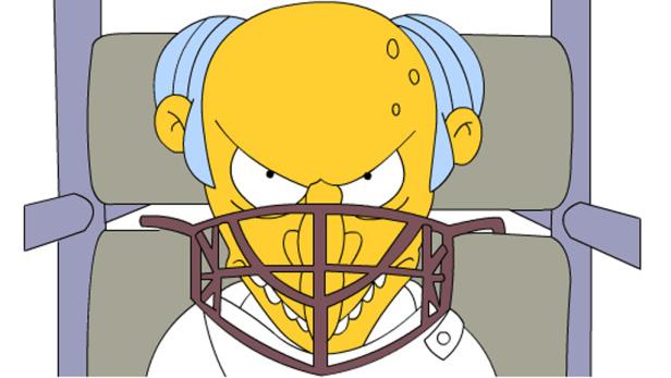 Montgomery Burns mit einem Maulkorb im Rollstuhl, der böse dreinblickt.