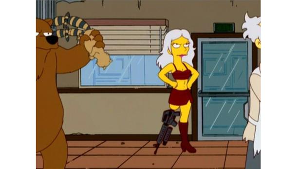 Ein Bär hält ein Stofftier hoch, während eine Frau mit einem Maschinengewehr am Bein daneben steht.