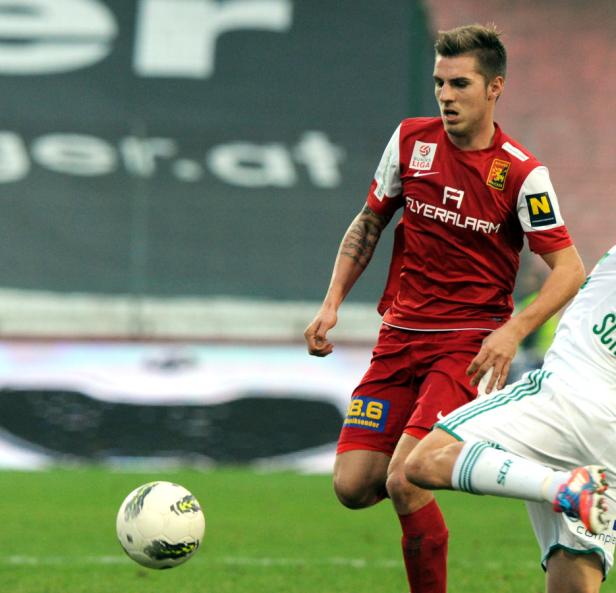Ein Fußballspieler in roter Spielkleidung während eines Fußballspiels.