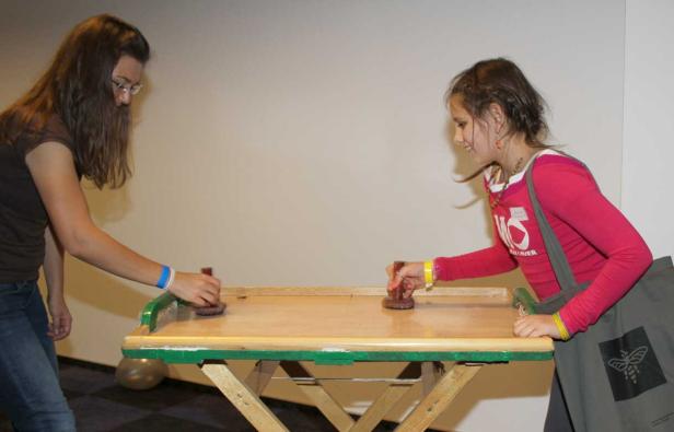 Zwei Mädchen spielen an einem Tisch Air Hockey.