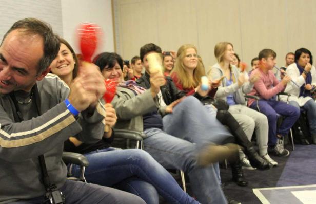 Eine Gruppe von Menschen sitzt und spielt Musikinstrumente wie Rasseln und Flöten.