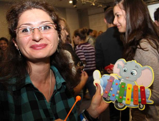 Eine Frau hält ein Spielzeugxylophon in Form eines Elefanten, während eine andere Frau im Hintergrund steht.