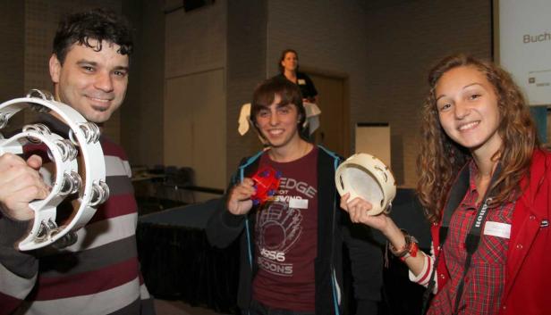 Drei junge Leute halten Musikinstrumente in die Kamera.