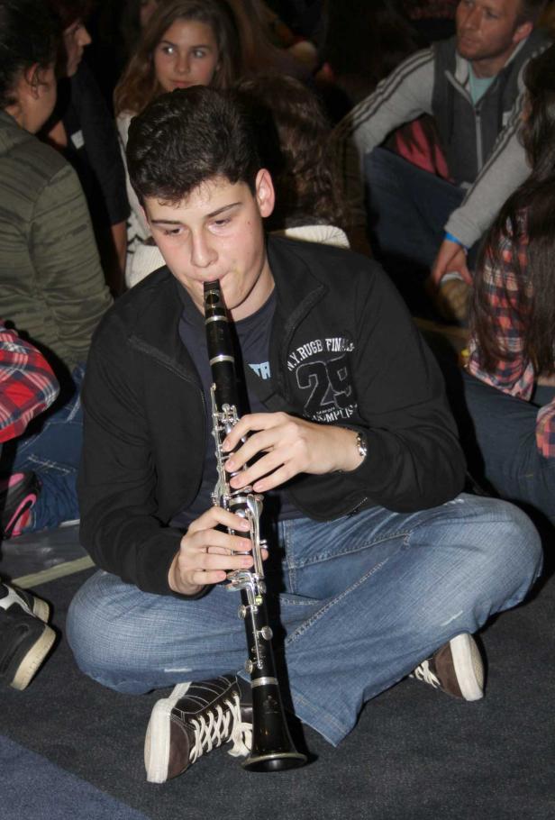 Ein junger Mann sitzt im Schneidersitz und spielt Klarinette.