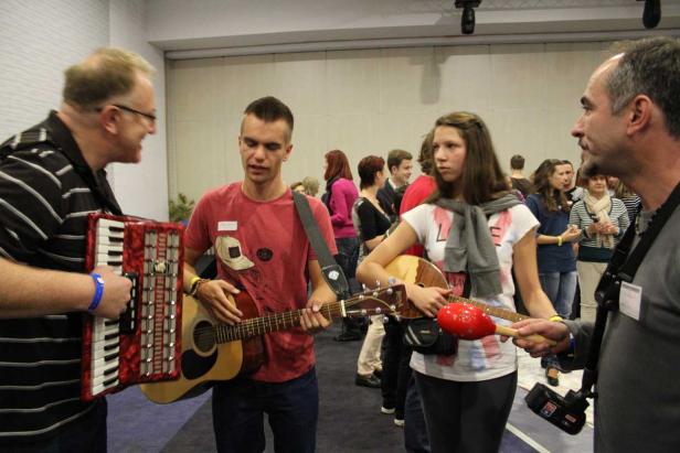 Eine Gruppe von Musikern spielt Akkordeon, Gitarre und andere Instrumente vor Publikum.