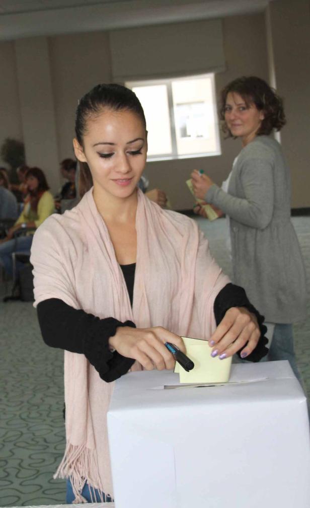 Eine Frau wirft einen Zettel in eine Wahlurne.