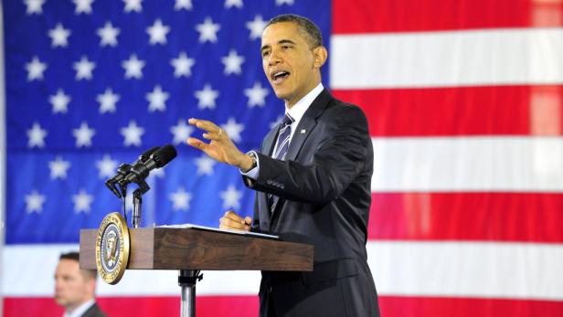 Barack Obama hält eine Rede vor einer amerikanischen Flagge.