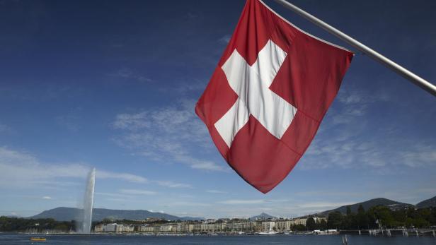 Die Schweizer Flagge weht vor dem Genfersee und dem Jet d'Eau.