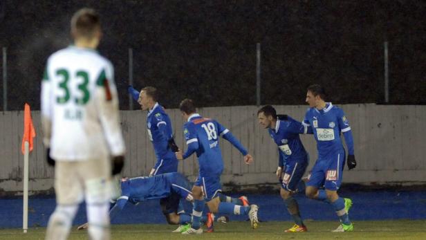 Fußballspieler in blauen Trikots jubeln über ein Tor.