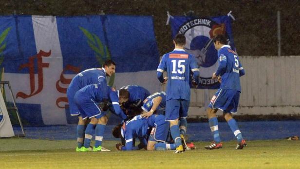 Eine Gruppe Fußballspieler in blauen Trikots feiert ein Tor.