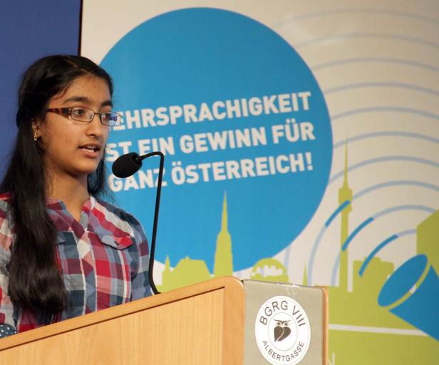 Eine junge Frau spricht an einem Rednerpult mit dem Logo des BRG VIII Albertgasse.