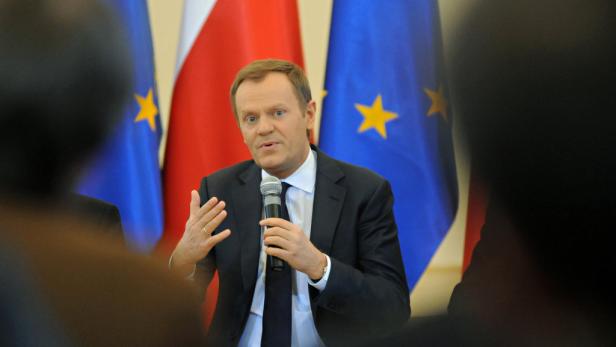 Donald Tusk spricht vor Flaggen der EU und Polens in ein Mikrofon.