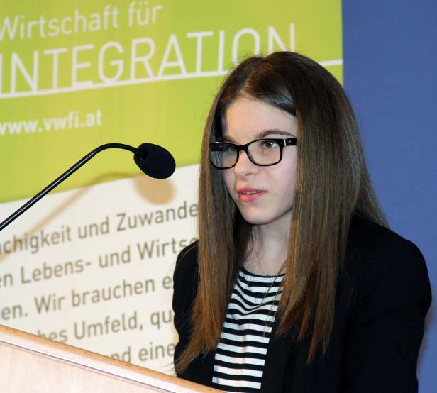 Eine junge Frau spricht an einem Rednerpult über Wirtschaft für Integration.