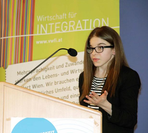 Eine junge Frau mit Brille hält eine Rede auf einer Veranstaltung zum Thema Integration.