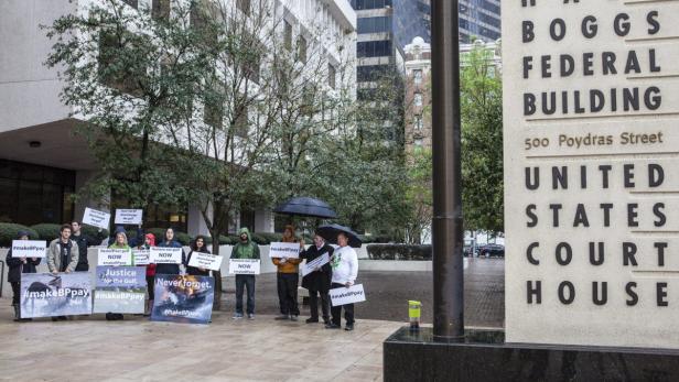 Eine Gruppe von Demonstranten steht vor dem Boggs Federal Building und fordert mit Schildern, dass BP zahlt.