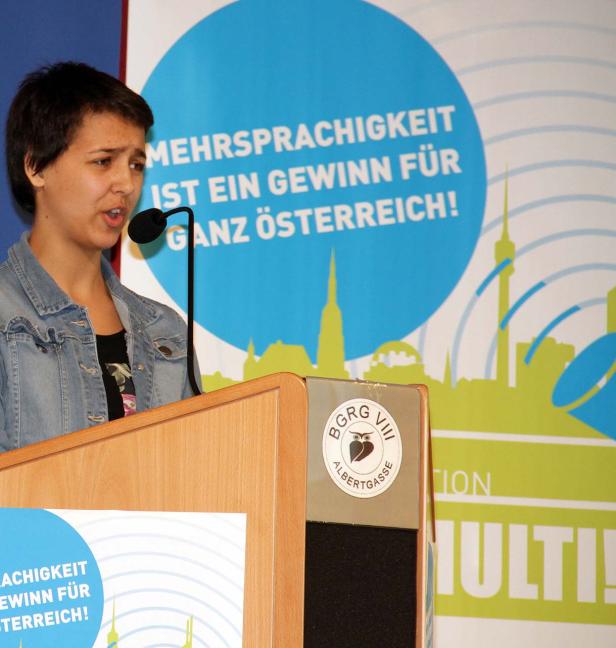Eine junge Frau spricht an einem Rednerpult über Mehrsprachigkeit in Österreich.