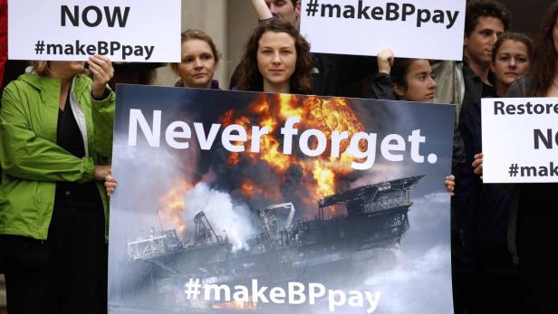 Demonstranten halten Schilder mit der Aufschrift „Never forget“ und „#makeBPpay“.