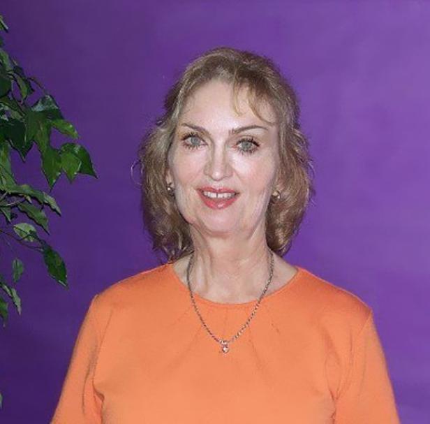 Eine Frau mit blonden Haaren lächelt vor einem lila Hintergrund.
