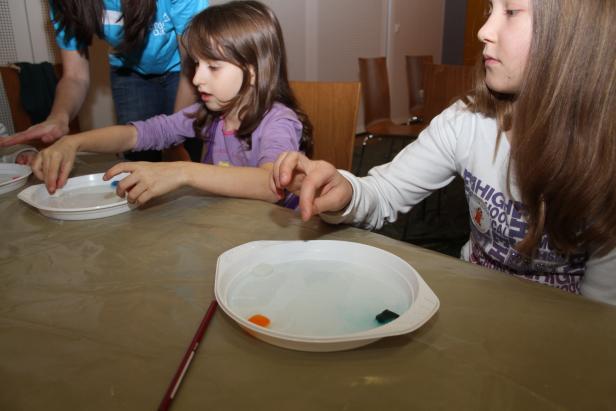 Zwei Mädchen spielen mit kleinen Gegenständen in mit Wasser gefüllten Schalen.