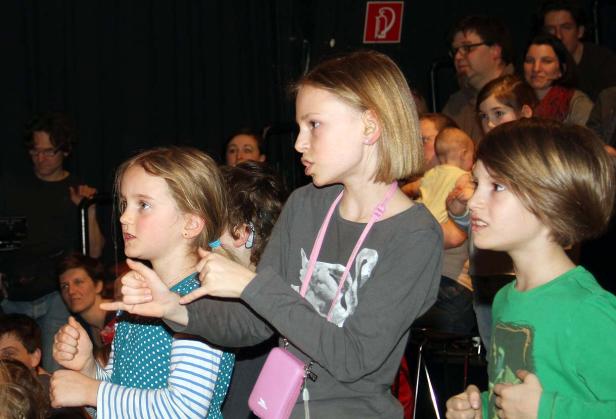 Mehrere Kinder scheinen aufmerksam einer Aufführung zu folgen.
