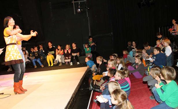 Eine Frau führt ein Theaterstück für eine Gruppe von Kindern auf.