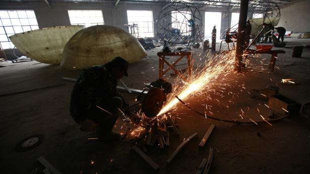 Ein Mann schneidet Metall mit einer Schleifmaschine, Funken sprühen.