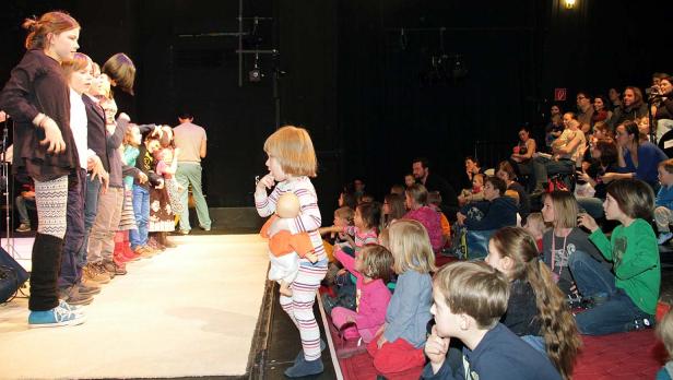 Kinder stehen auf einer Bühne vor einem Publikum.