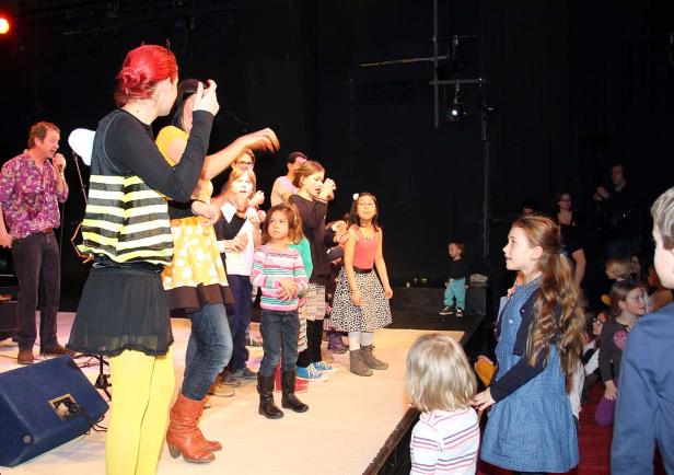 Eine Gruppe von Kindern und Erwachsenen steht auf einer Bühne.