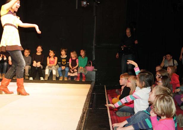 Eine Frau führt eine Gruppe von Kindern auf einer Bühne an.