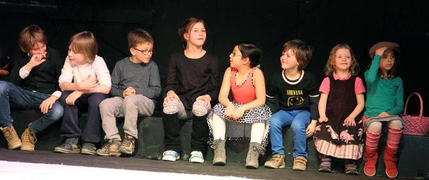 Eine Gruppe von Kindern sitzt auf einer Bühne.