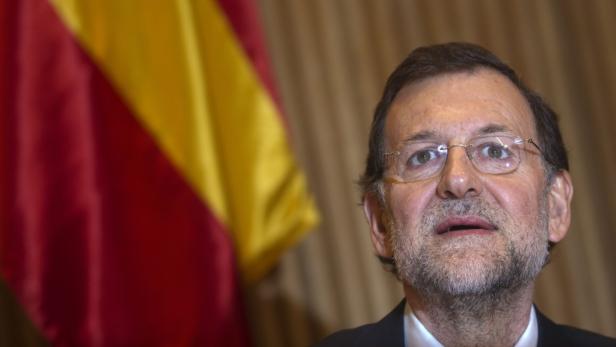 Mariano Rajoy steht vor der spanischen Flagge.